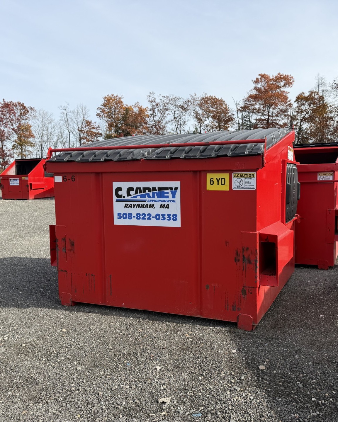 6 yard, red, Carney Environmental front load can in front of an autumn background