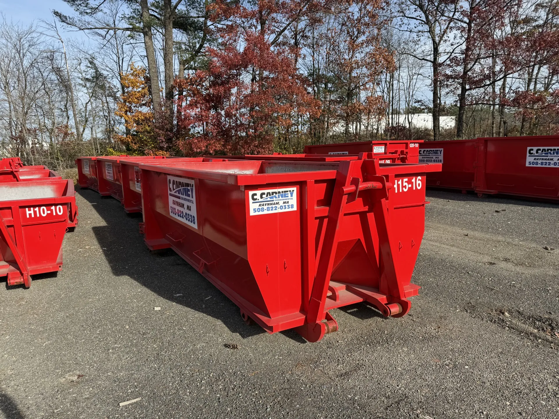 15 yard red Carney Environmental hooklift dumpster in a residential driveway