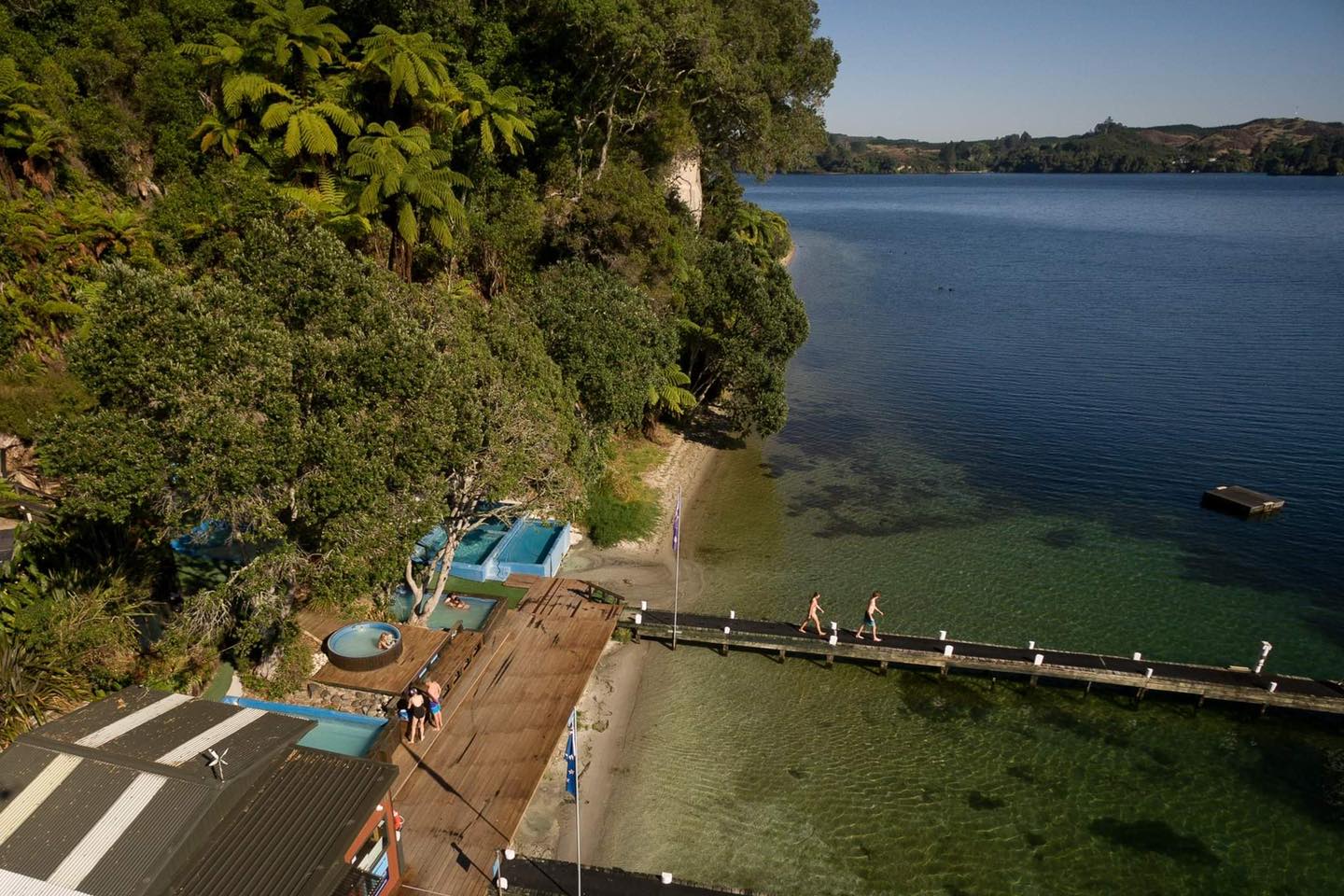 couple walking out onto the jetty at the lake rotoiti hotpools in rotorua