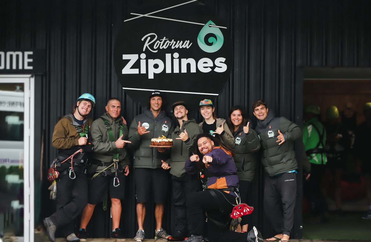the rotorua zipline team outside the zipline base holiding a cake celebrating the birthday of the zipline