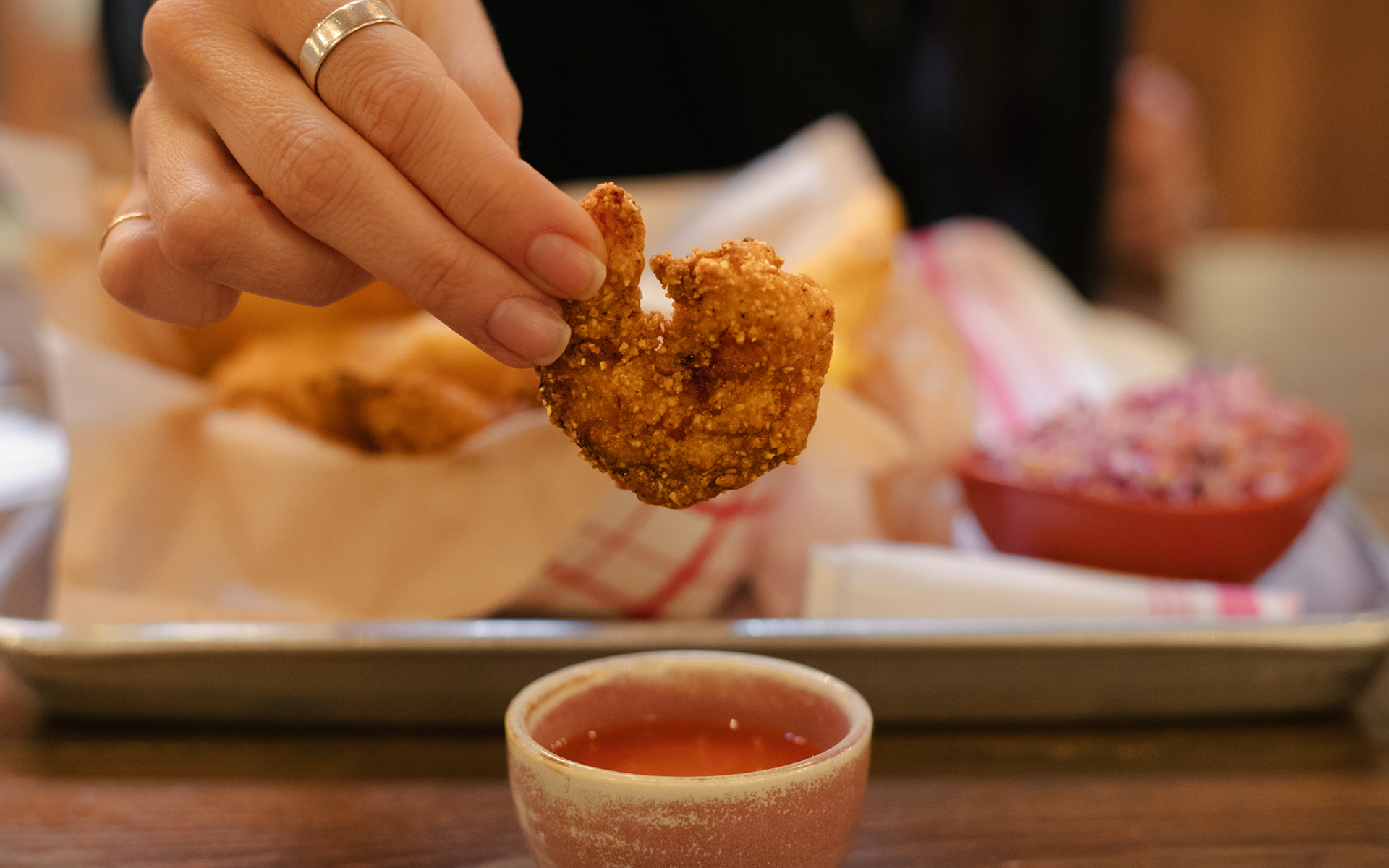Woman's hand holding a piece of fried shrimp