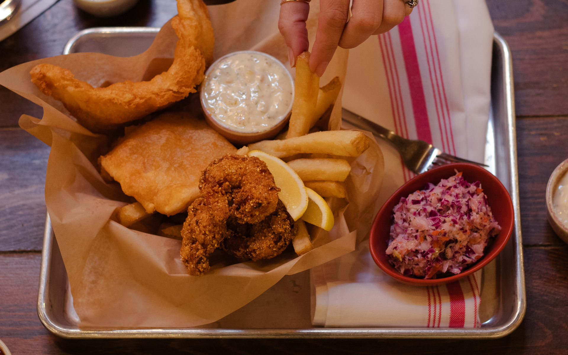 Tray with dish of fried fish, shrimp and chips with dish of coleslaw and dips