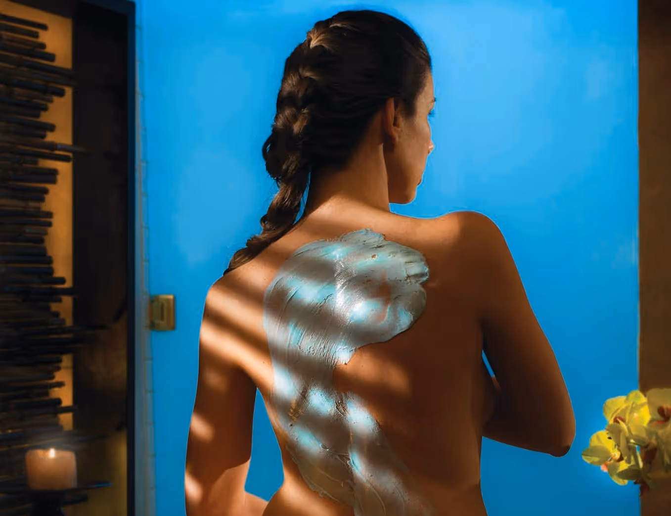 Womans back with clay mask with hair in braid facing away
