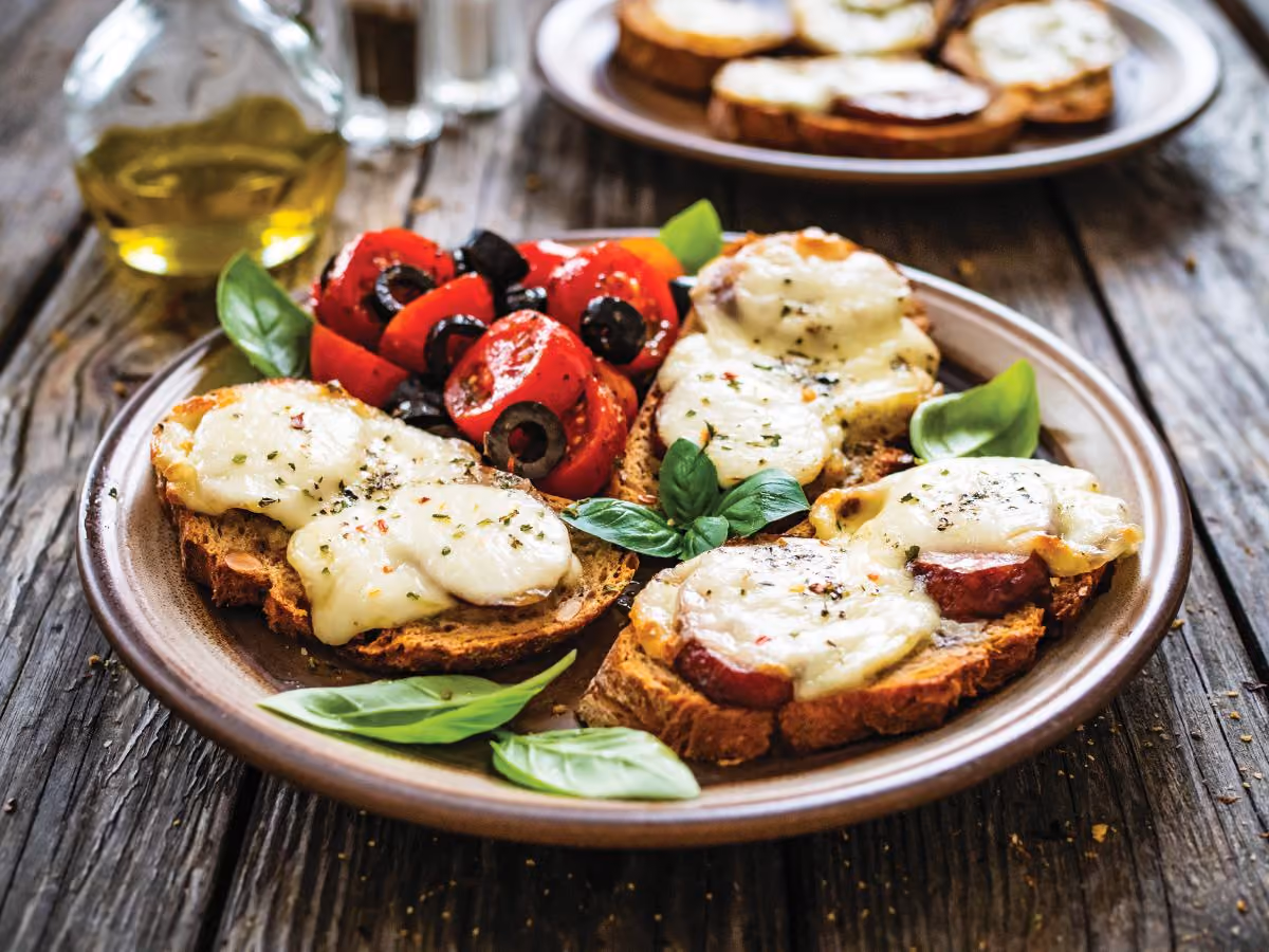 Plate of sliced bread with tomatoes and basil