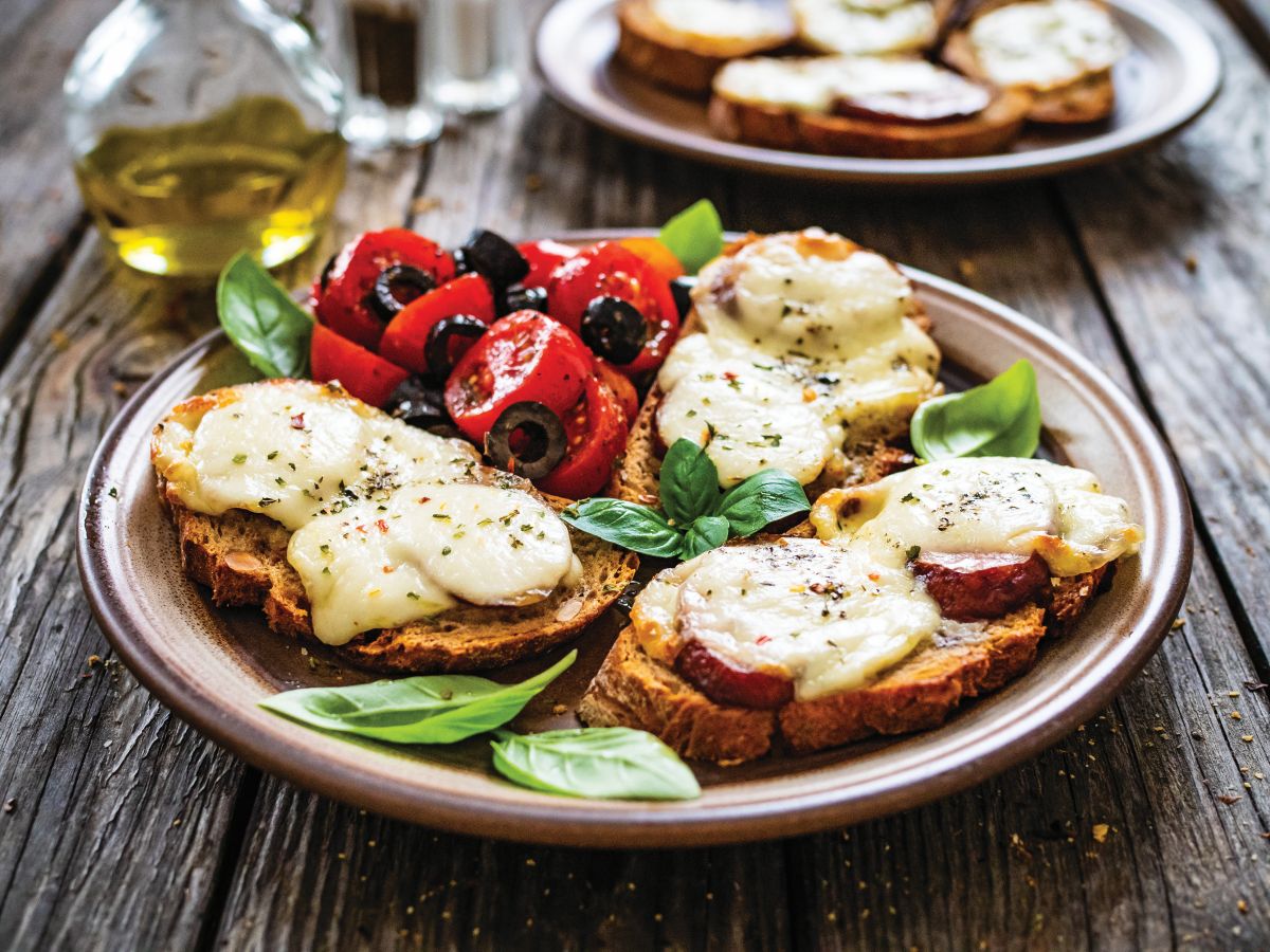 Plate of sliced bread with tomatoes and basil