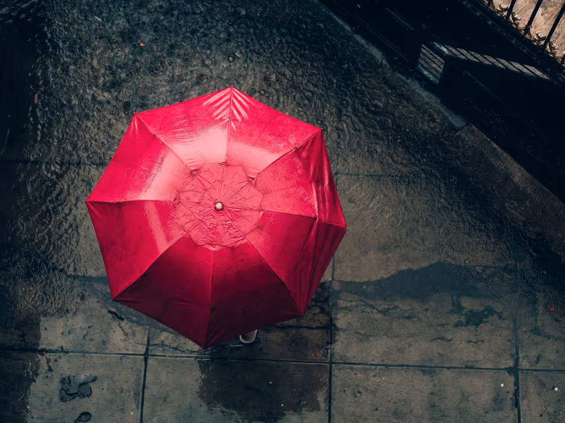 Bright red umbrella on wet concrete ground with reflections