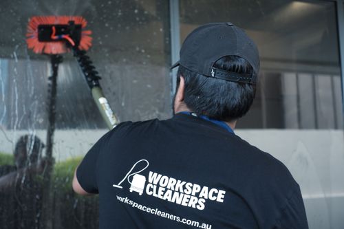 A man cleaning a windows with a water fed window cleaning system
