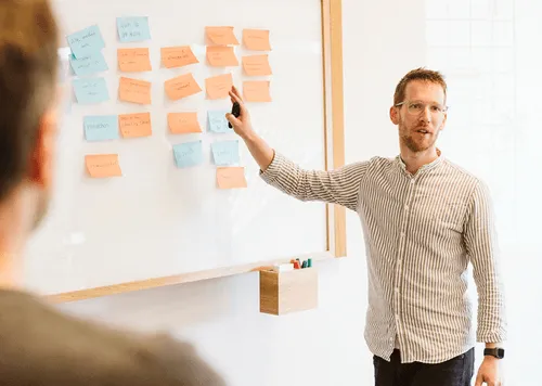 Ein Mann zeigt auf eine Tafel mit Post-its