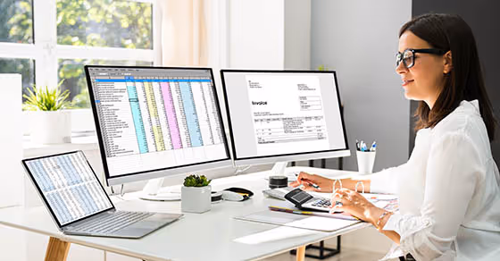person at desk working in front of two monitors and a laptop