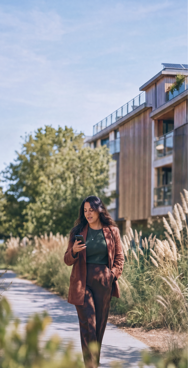 A HappyCo customer walking near a multifamily property, checking their phone