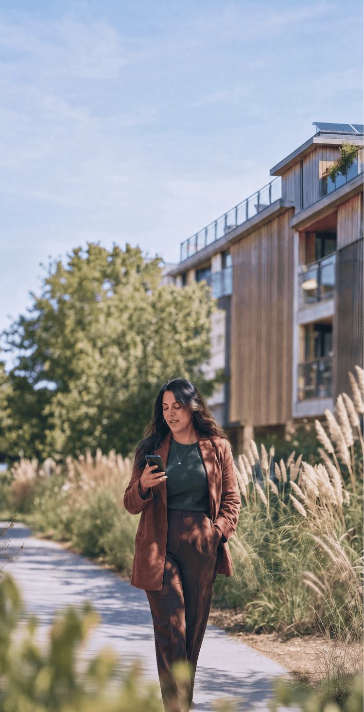 A HappyCo customer walking near a multifamily property, checking their phone