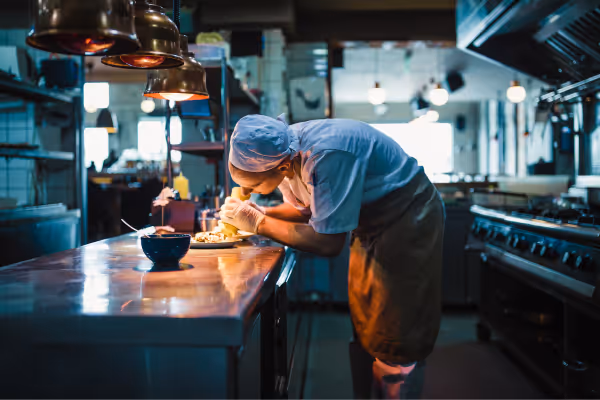 En kokk som forbereder en rett på et industrielt kjøkken