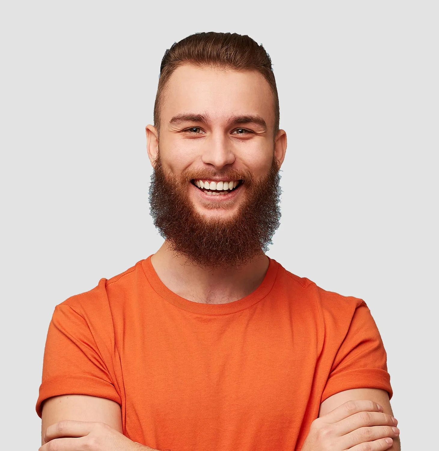 Smiling man with a full beard and styled hair wearing an orange T-shirt with folded sleeves, arms crossed.
