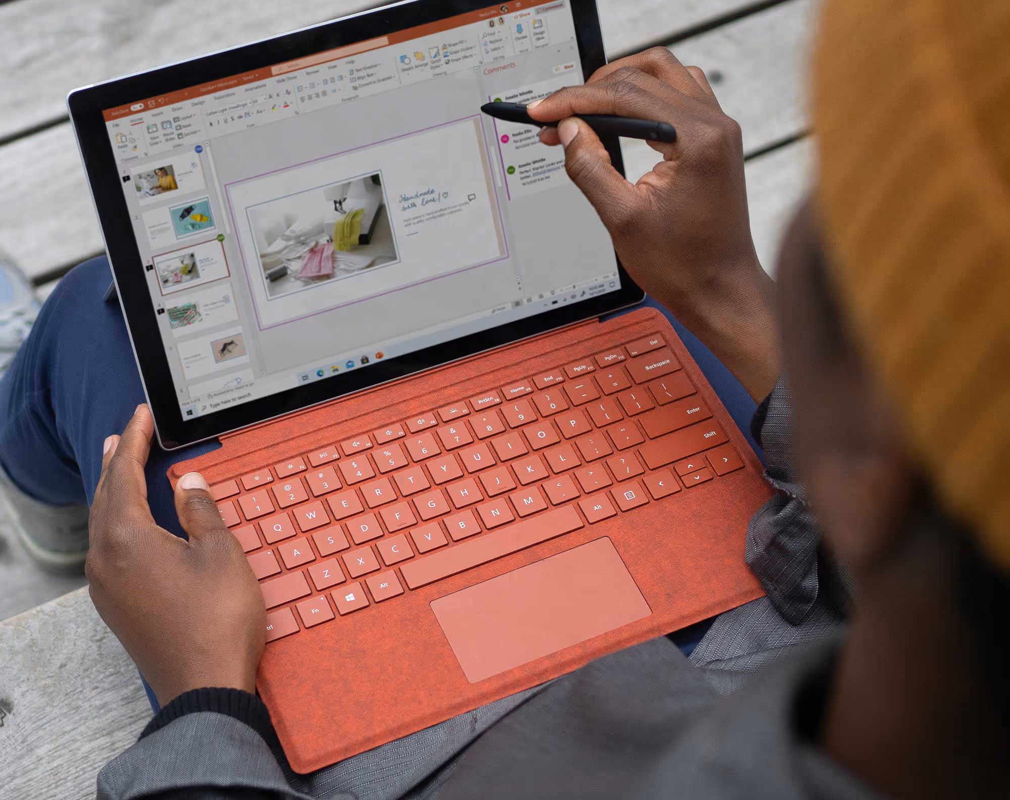 Person using stylus to edit a PowerPoint presentation on a laptop with a red keyboard cover.