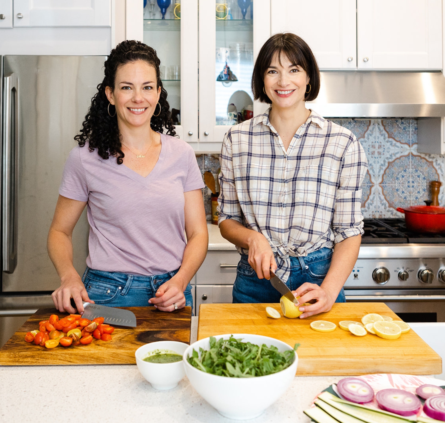 Christine and April in kitchen. Christine is slicing tomato and April is slicing lemon