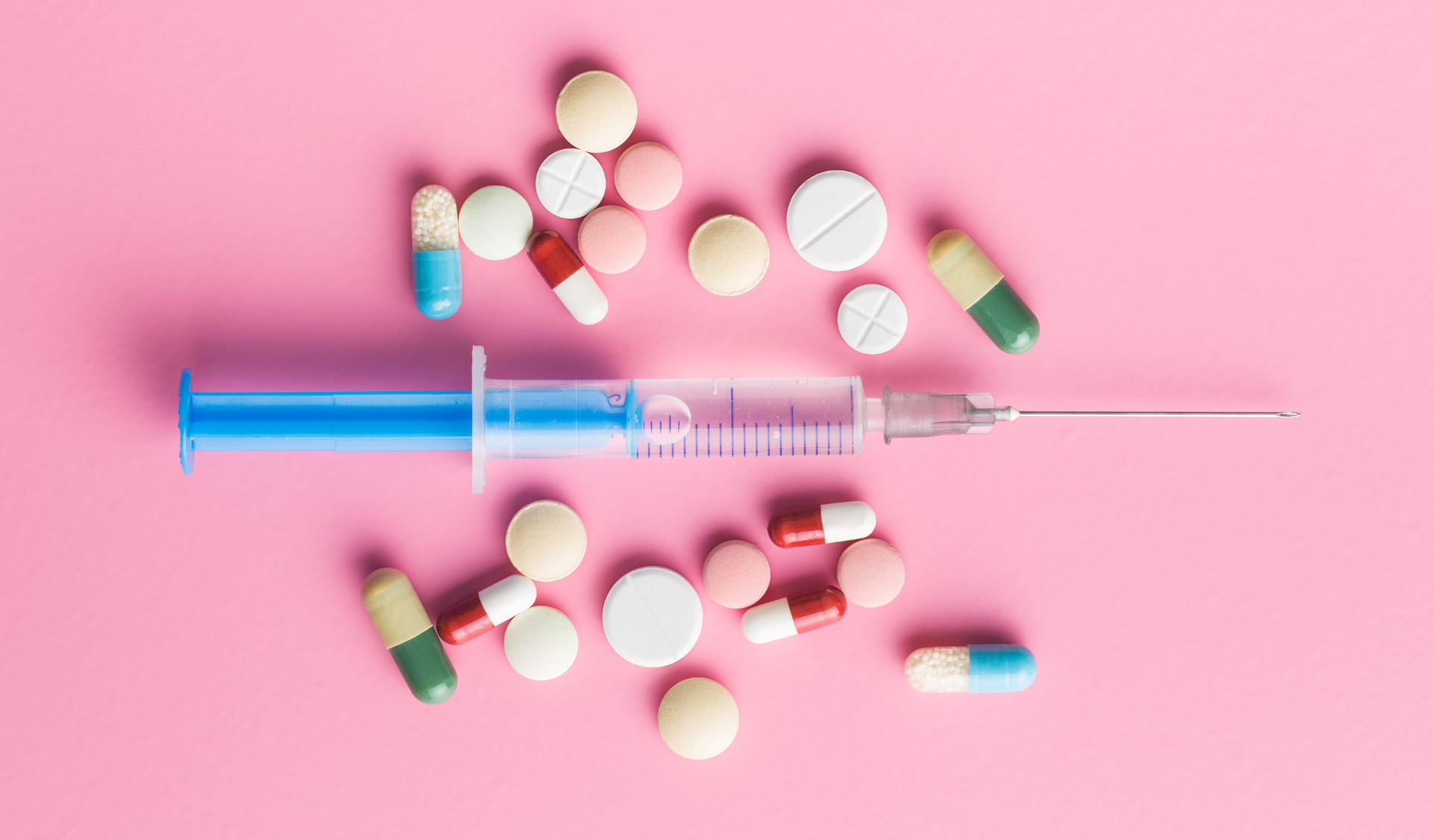 Pills and syringes on pink backgroun