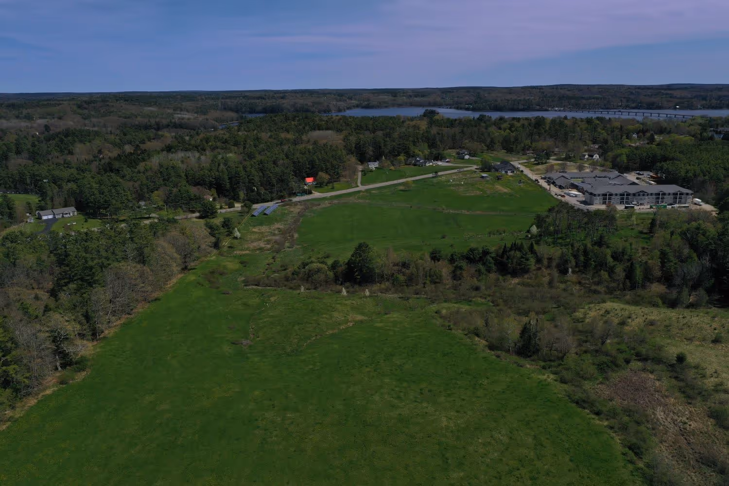 Aerial view of green fields, forests, and buildings near a lake
