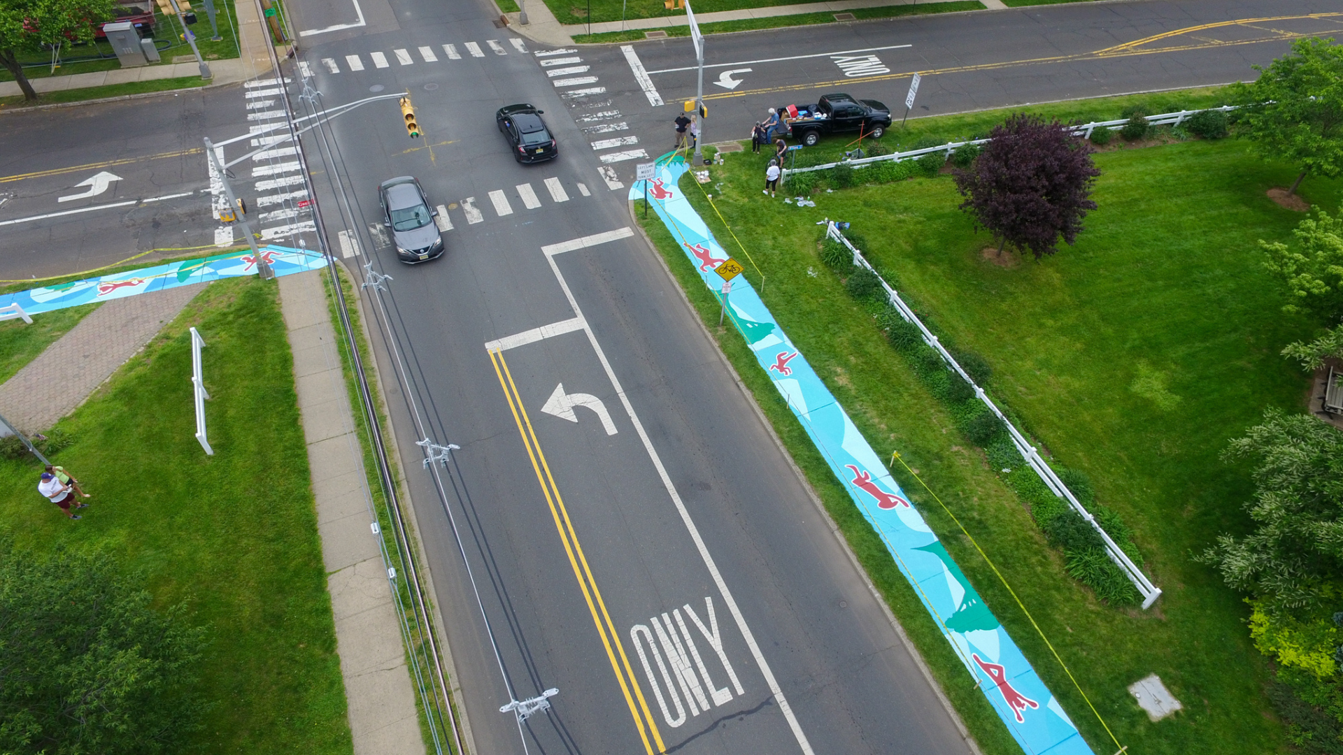 Two male musicians performing on stage, one playing an orange electric guitar and the other wearing a hat and beige vest singing or dancing.