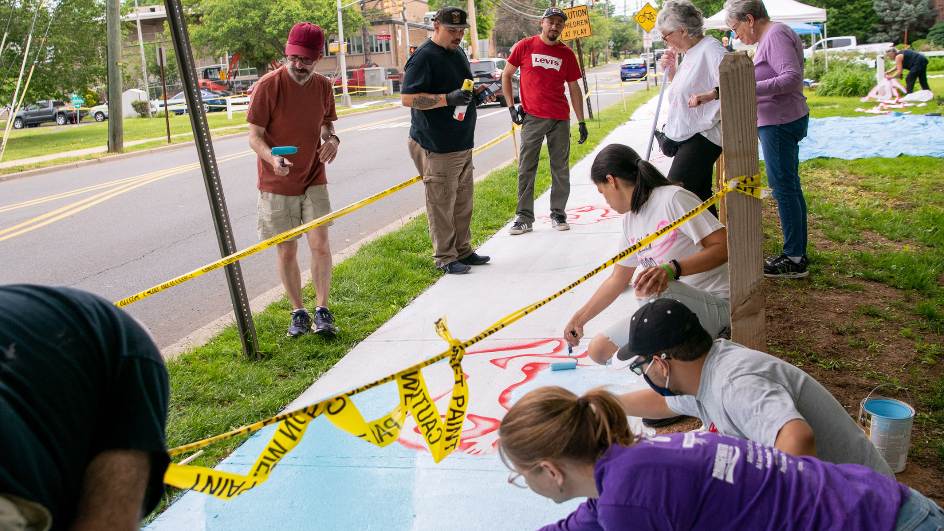 Display of assorted handmade pottery including bowls, mugs, and vases arranged on a red cloth with a colorful mural background.