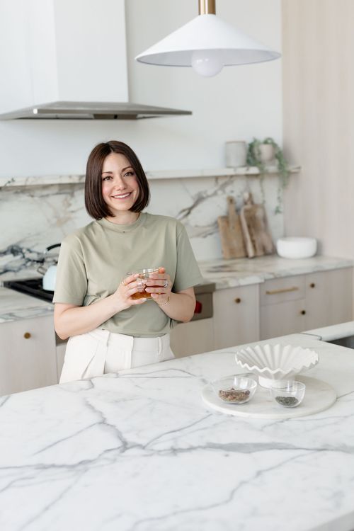 Doctor Margot ND sitting on couch holding glass