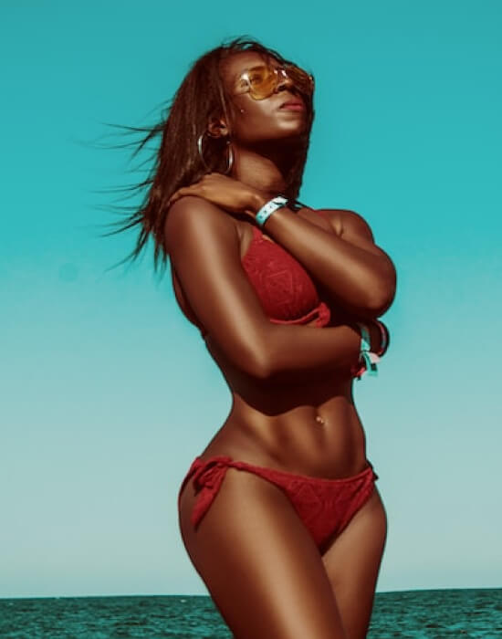 A model wearing a red bikini along with her sunglasses posing in a green background