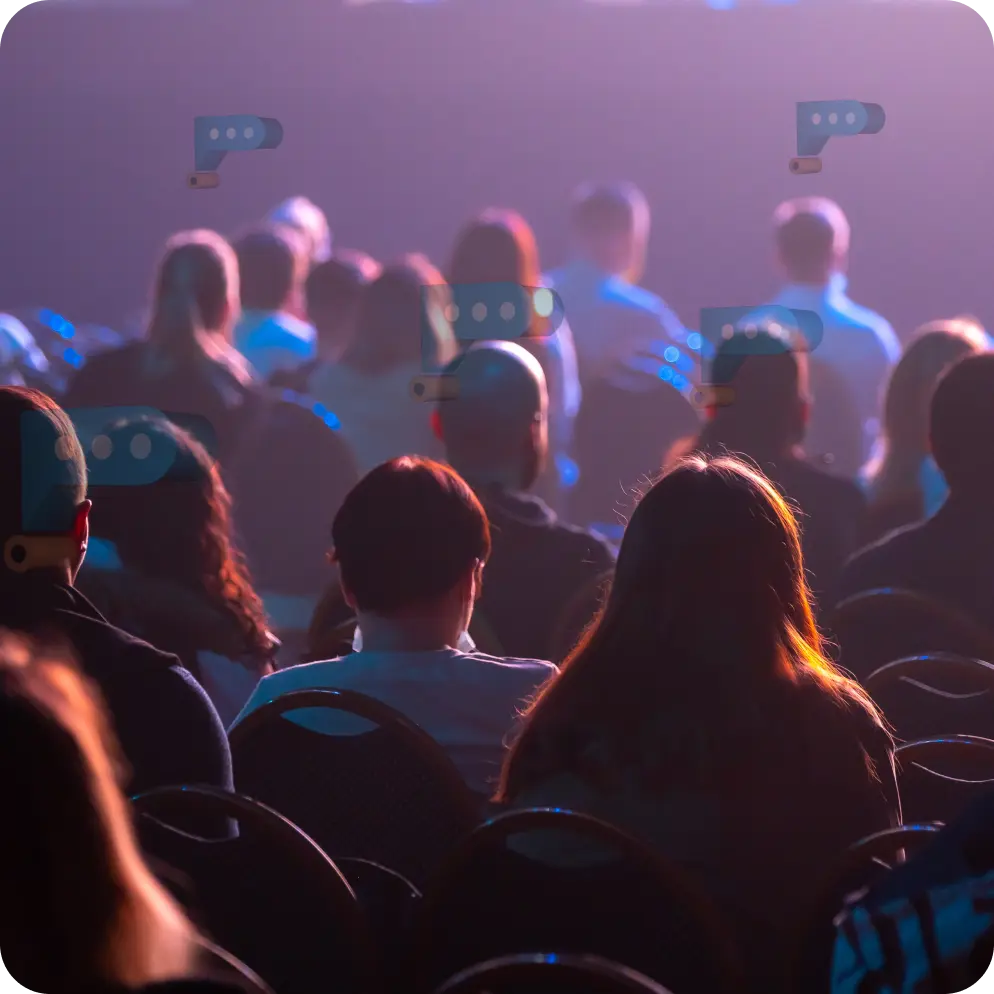View from the back of a crowded movie theater of an audience watching a bright screen, illustrating how The People Platform measures audience engagement