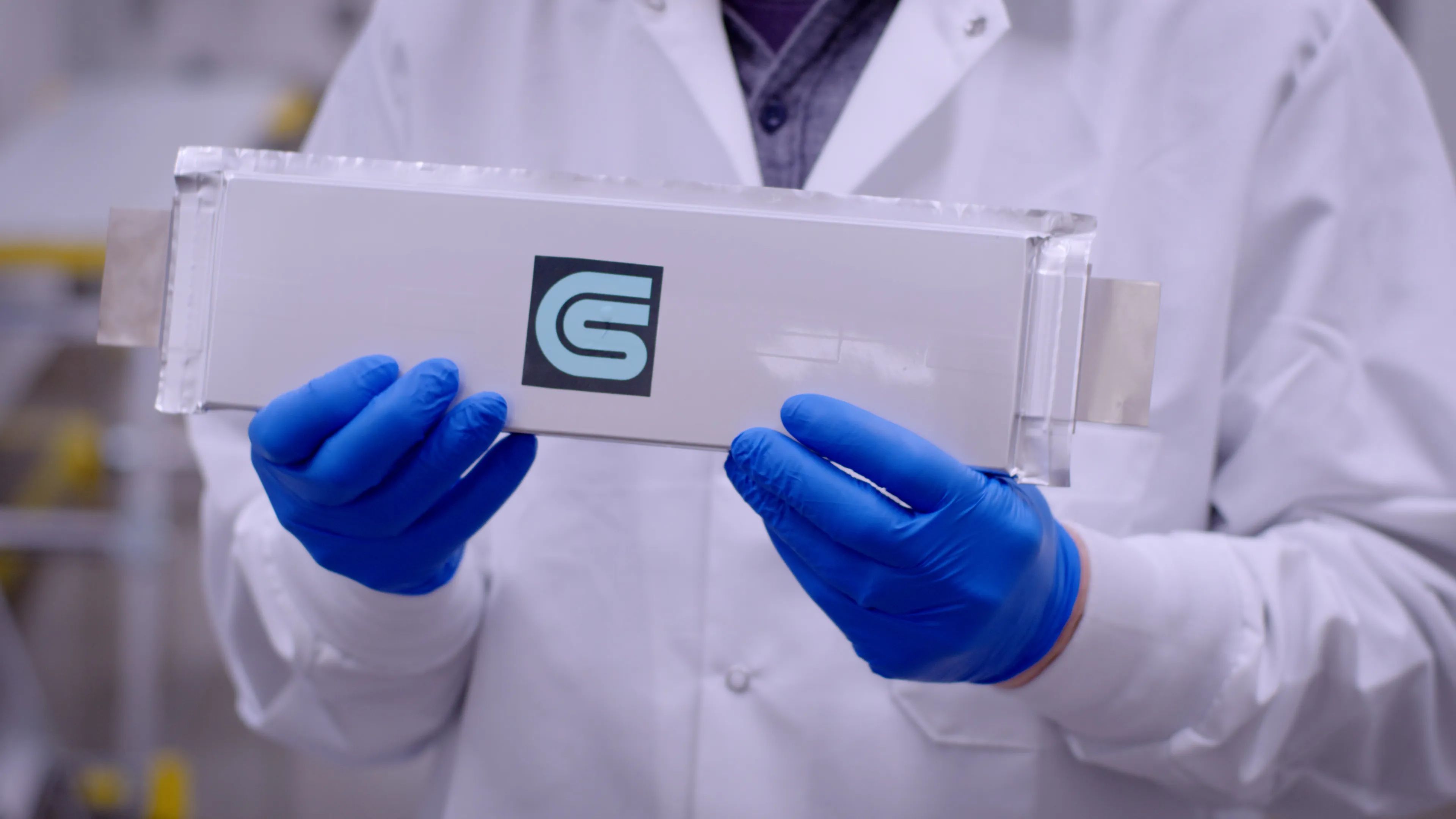 A gloved technician holding a Coreshell battery cell