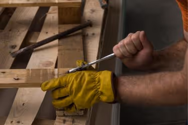 Man repairing pallets in house