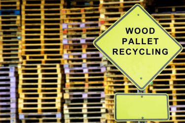 Stacks of recycled pallets with the sign that says "Wood pallet recycling"