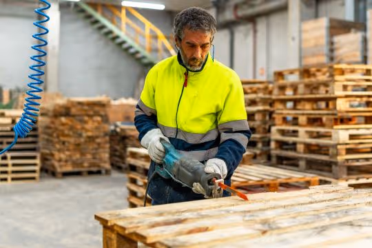 Sustainable Pallet Manufacturing Trends - Man fixing an old wooden pallet