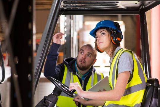 Safety Best Practices in Palletizing - Woman being trained to use the forklifter