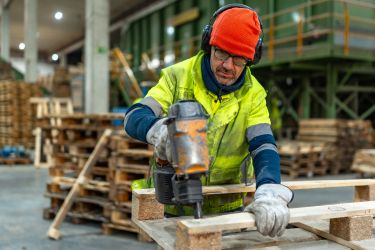 Old man working with a nail gun