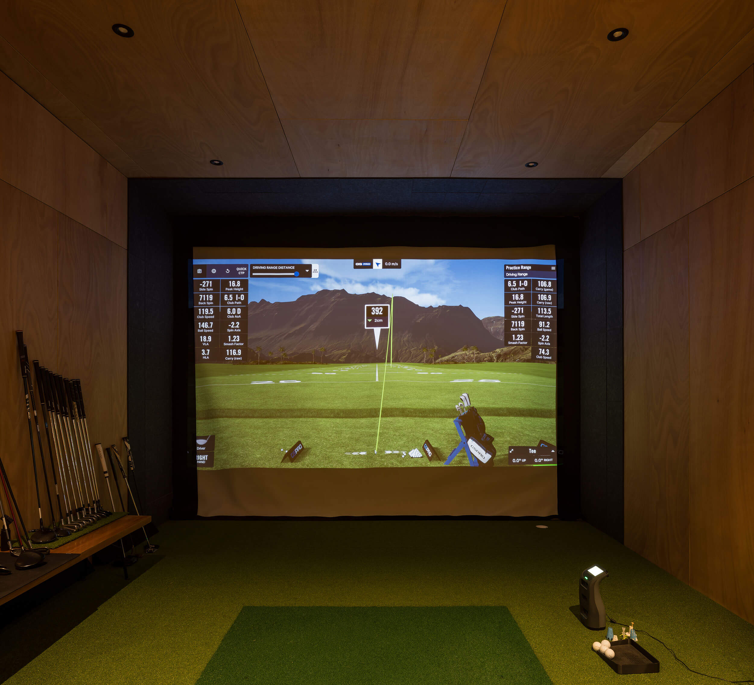 Golf simulator hitting bay with projector screen, turf and timber-lined walls
