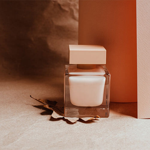 A perfume bottle in front of a wall.