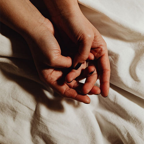 Hands on bed sheets.