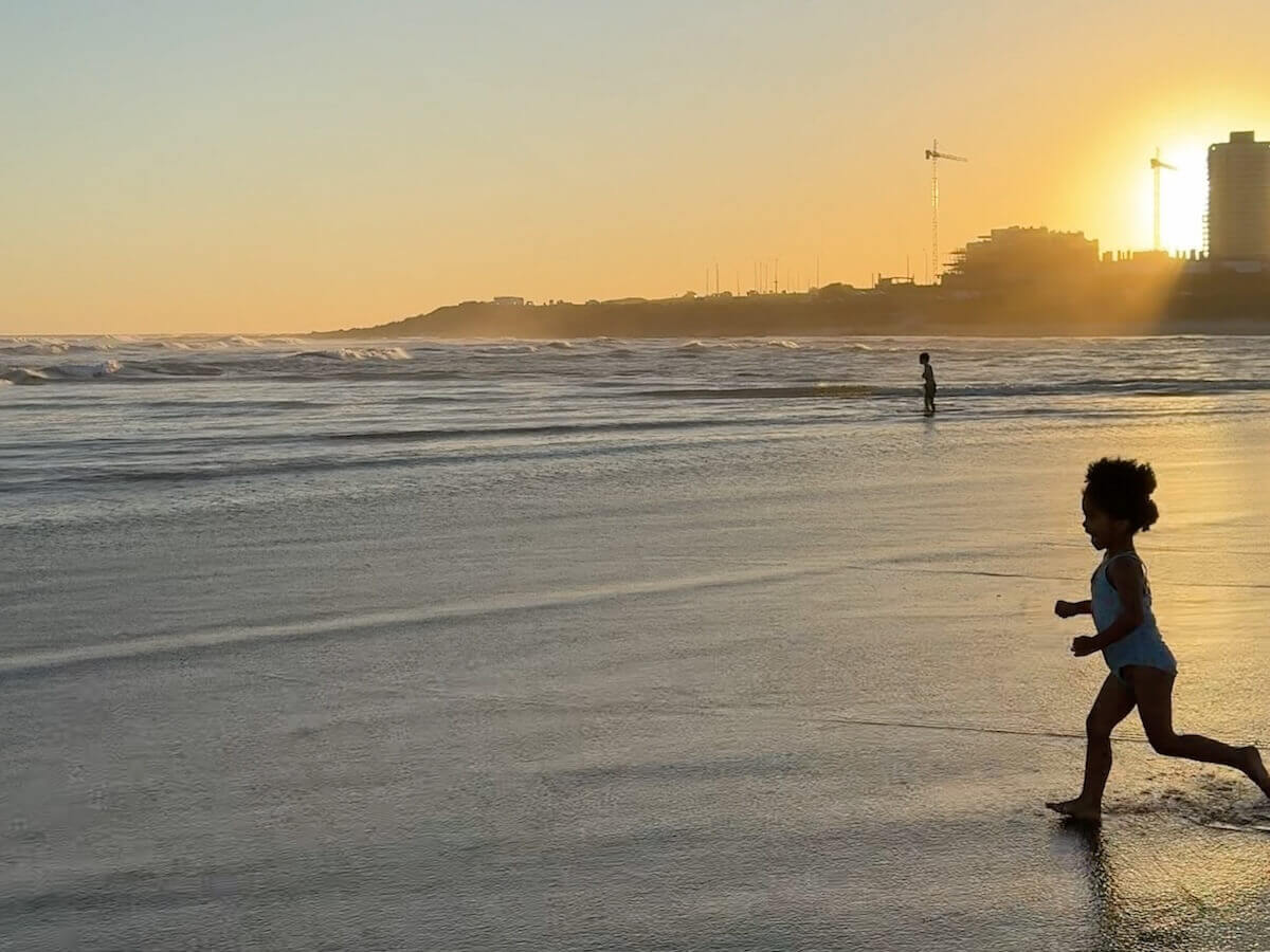 A young child runs into the ocean at La Barra Uruguay