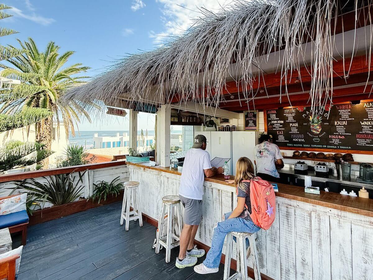 A father and daughter order breakfast at a beach cafe overlooking the ocean at La Barra Uruguay