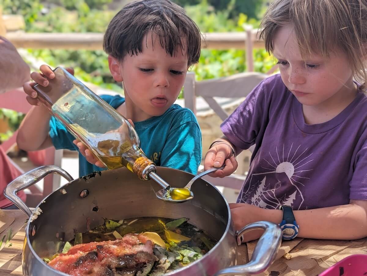 Kids from a big travel family make dinner in a large pot