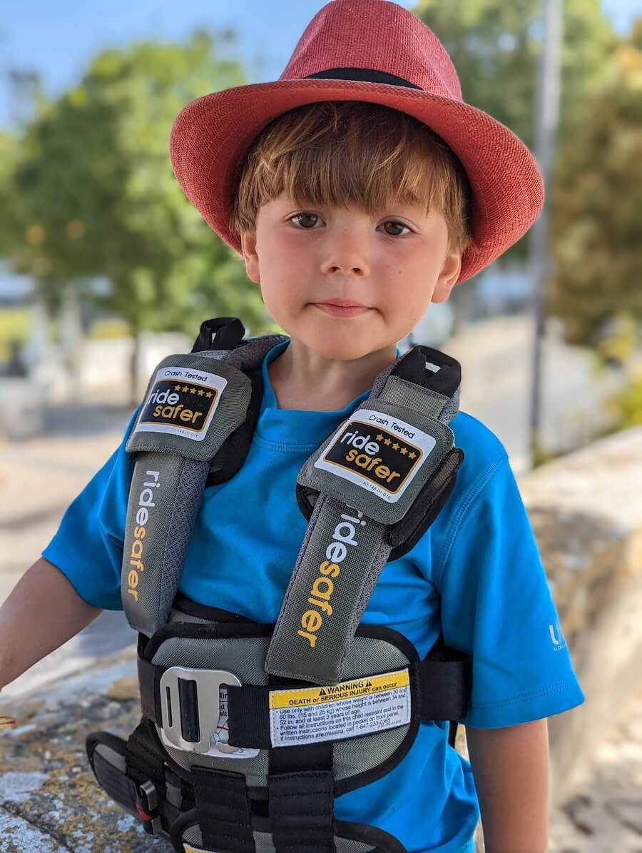 A child wearing a ride safer car restraint