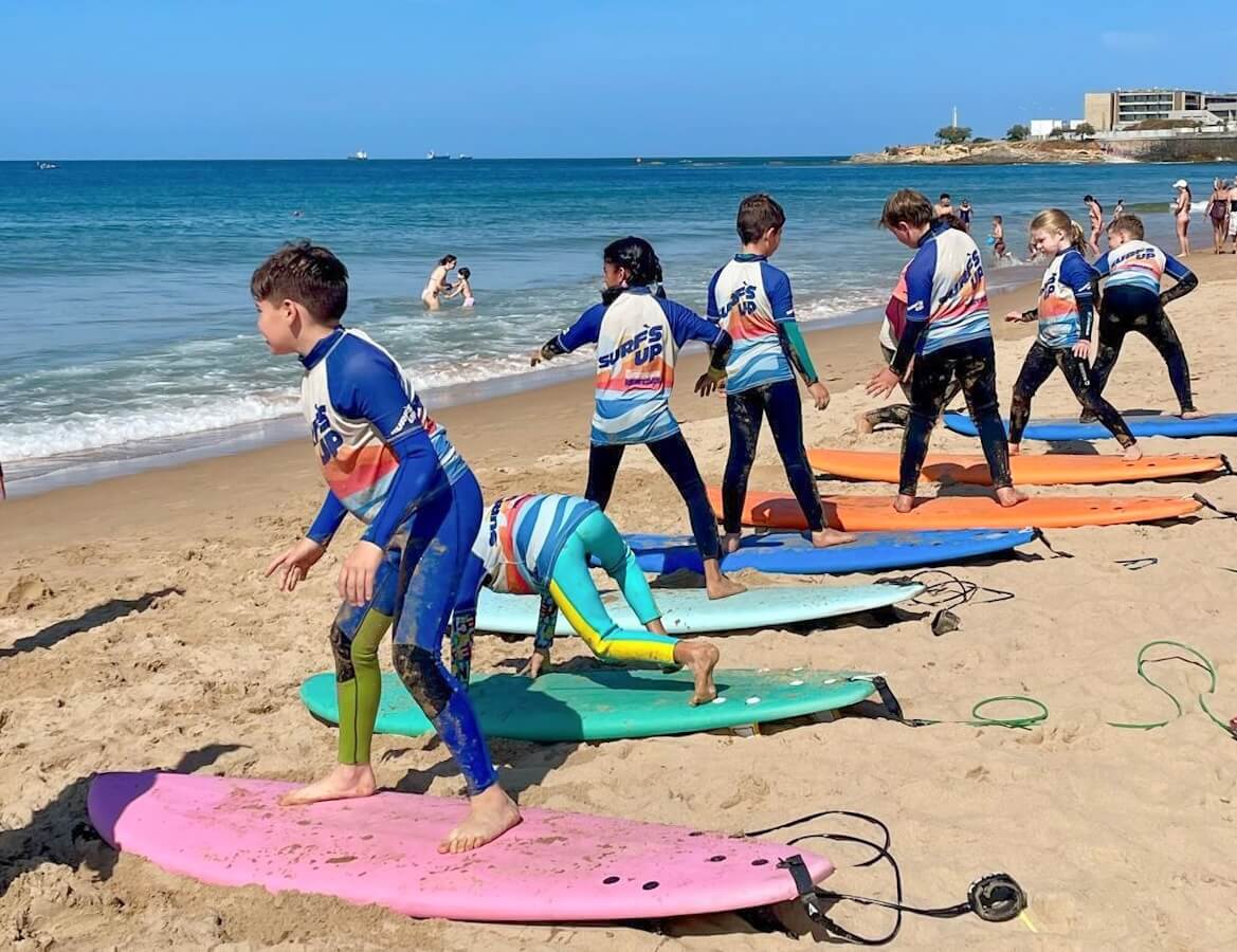 Kids lined up on surfboards during a surf lesson in Portugal