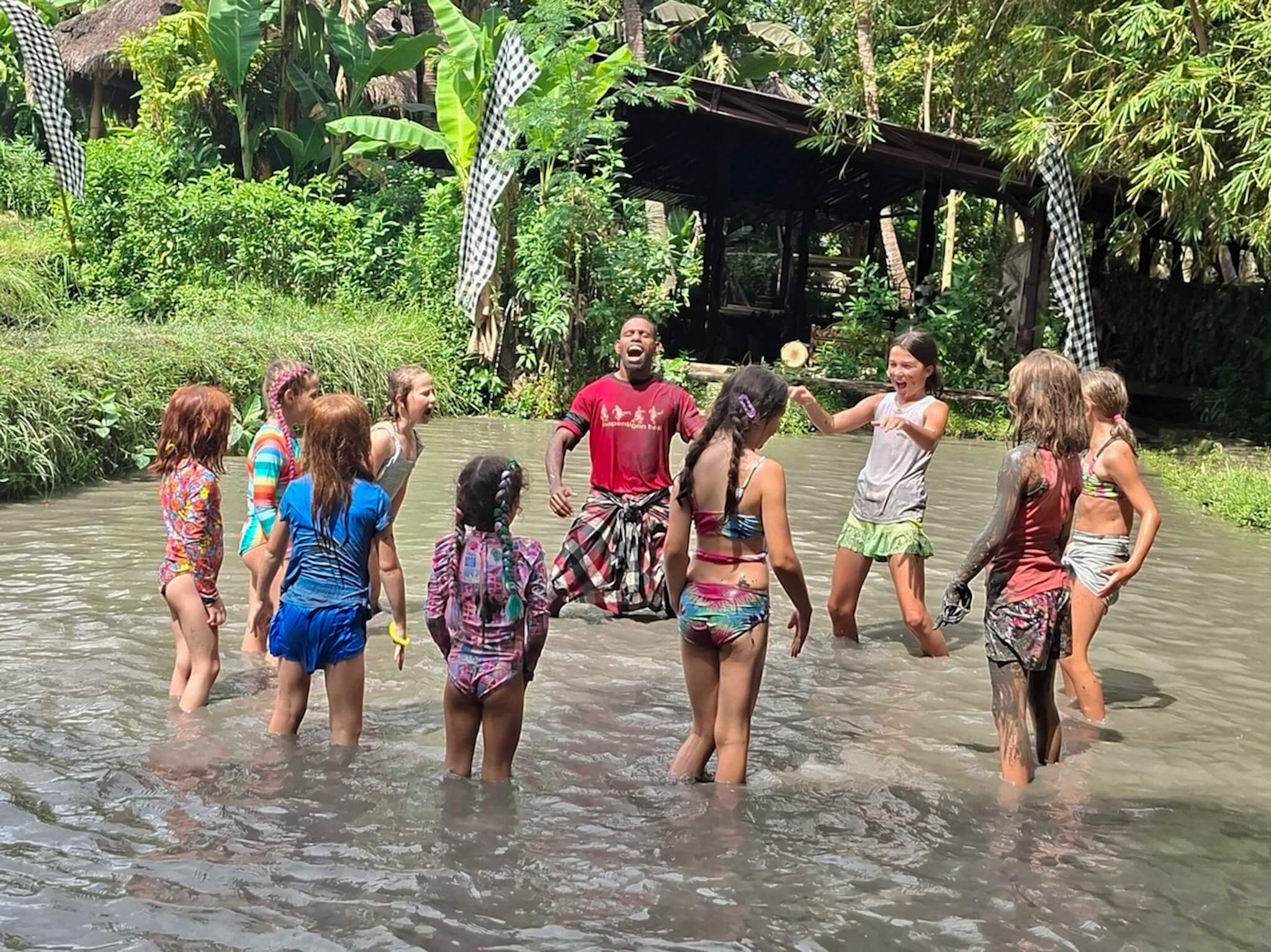 A group of kids having fun and playing in a muddy river in Bali
