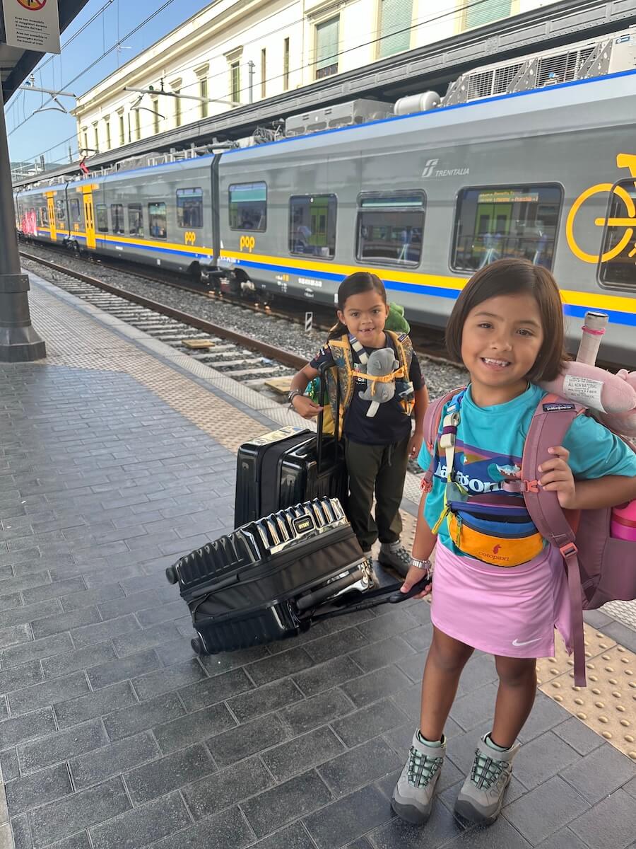 Two girls at the train station slow traveling in Italy on a Boundless Life adventure.