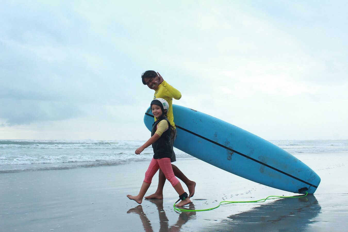 A child and her surf instructor in Bali - a family travel guide.