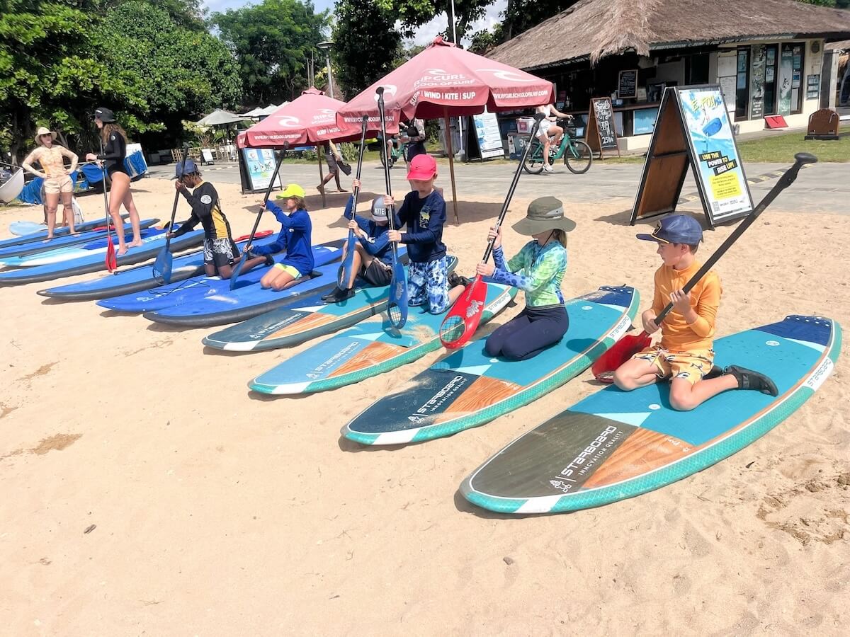 A group of kids take paddle boarding lessons in Sanur, Bali