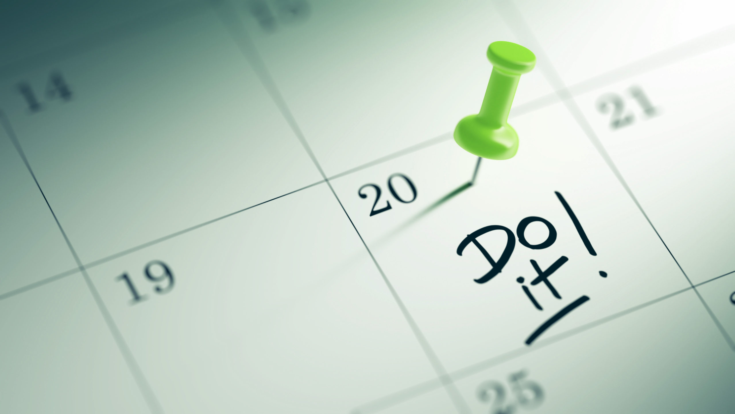 Concept image of a Calendar with a green push pin. Closeup shot