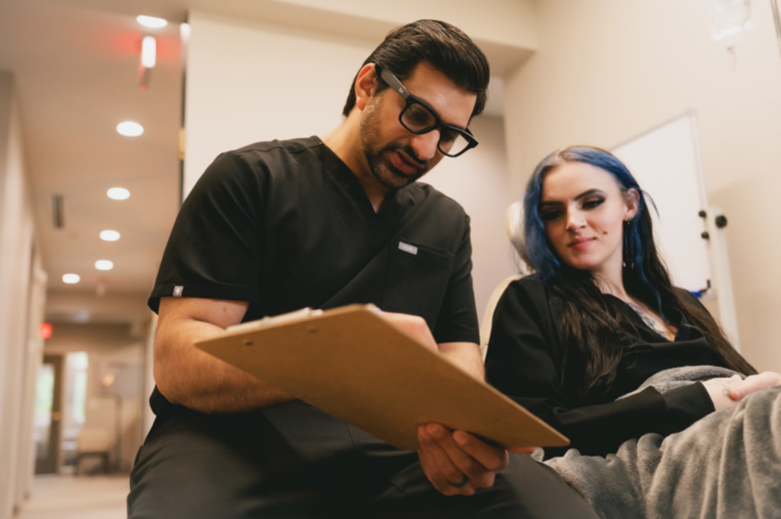 Male dentist and female team member reviewing patient records together