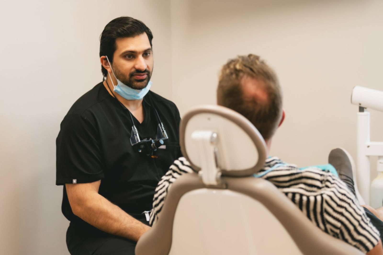 Dentist discussing dental implant options with a patient in treatment room.