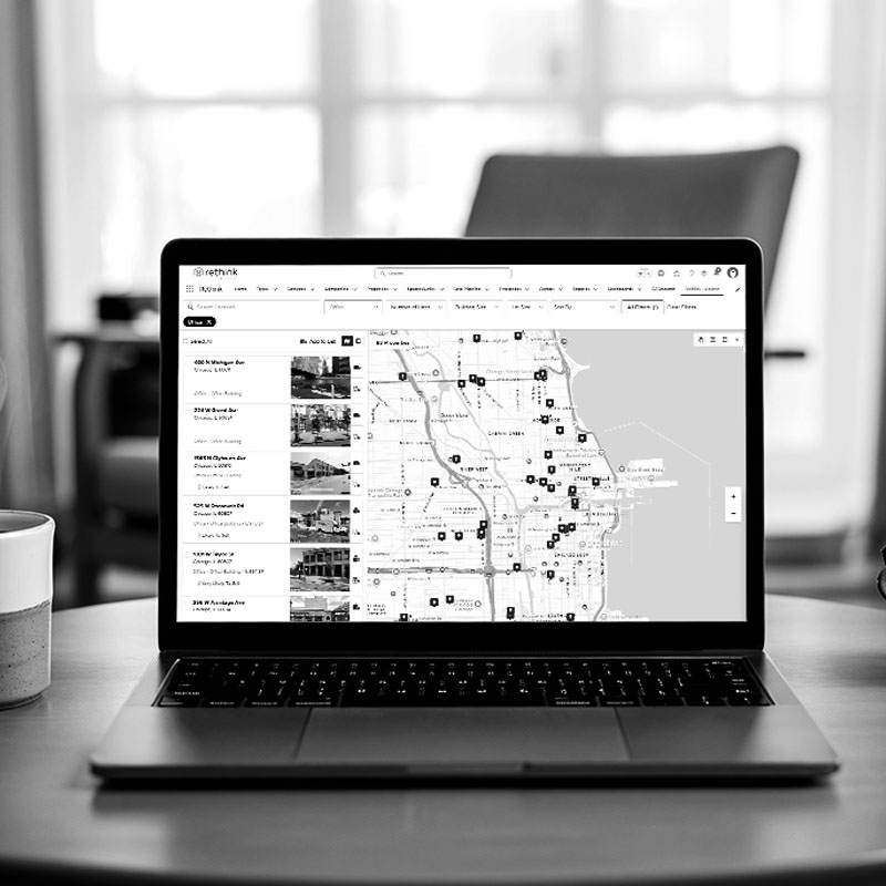 Computer sitting on desk with a mockup of Rethink+ property search feature