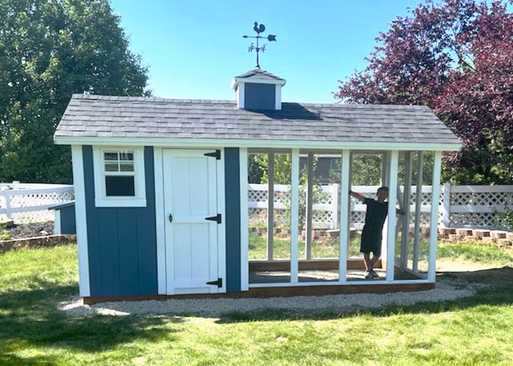 A 6 foot by 14 foot Coop De'Ville chicken coop with a boy standing in the chicken Run.  