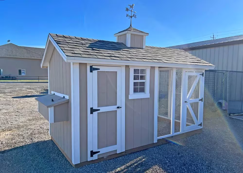 A 6 x 12 foot Coop De'Ville chicken coop in tan and white with a cupola and weather vane